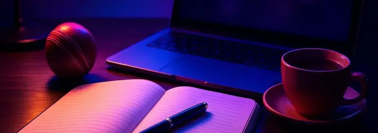 Writing desk under lamp light with a notebook, a pen and a laptop
